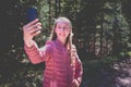 Young teen girl traveler taking selfie on mobile phone in a summer day forest. girl looking at smartphone camera Royalty Free Stock Photo