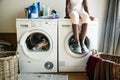 Young teen girl waiting for clothes to be washed from washing machine Royalty Free Stock Photo