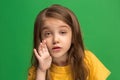 The young teen girl whispering a secret behind her hand over green background