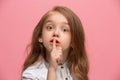 The young teen girl whispering a secret behind her hand over pink background