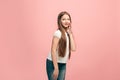 The young teen girl whispering a secret behind her hand over pink background Royalty Free Stock Photo