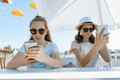 Young teen girls with mobile phones. Sit in a street cafe, sunny summer day in recreation and entertainment area Royalty Free Stock Photo