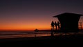Young teen girls silhouettes, lifeguard watch tower, friends on pacific ocean beach, California USA.