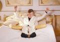 Young teen guy wearing white business suit and lying on the bed in his Golden room, stretching and yawning