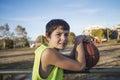 Young teen male with sleeveless standing on a street basket court while smiling at camera