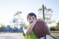 Young teen male with sleeveless standing on a street basket court while smiling at camera