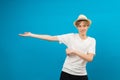 Young teen man points palms aside isolated on blue. Friendly well-looking boy paying your attention at copy space, best deal, sale Royalty Free Stock Photo