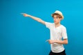 Young teen man points palms aside isolated on blue. Friendly well-looking boy paying your attention at copy space, best deal, sale Royalty Free Stock Photo