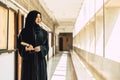 Young teen muslim niqab woman reading the Quran and faith The Holy Al Quran in University building. Arab black chador lady