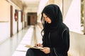 Young teen muslim niqab woman reading the Quran and faith The Holy Al Quran in University building. Arab black chador lady