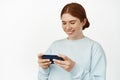 Young teen redhead girl playing video games on her phone, watching video live stream on cellphone, laughing and smiling Royalty Free Stock Photo