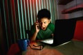 Young Teen using a cellphone or smartphone in front of a laptop computer Royalty Free Stock Photo