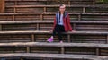 Young teen woman seats audience outdoor theater wooden benches city park