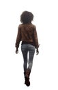 young teen woman walking away. African american woman wearing a brown leather jacket and light jean pants and boots. Royalty Free Stock Photo