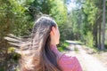 Young teen woman walking on a trail in a summer sunny day forest.The girl`s hair is long. She relaxes in the fresh air Royalty Free Stock Photo