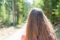 Young teen woman walking on a trail in a summer sunny day forest.The girl`s hair is long. She relaxes in the fresh air Royalty Free Stock Photo