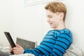 Young Teenage Boy Relaxing in Bed with Tablet Royalty Free Stock Photo