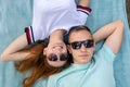 Young teenage couple in sunglasses laying together on blue cloth enjoying love relations