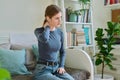 Young teenage female experiencing neck pain sitting on couch at home Royalty Free Stock Photo