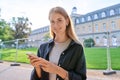 Young teenage female student using smartphone, looking at camera, outdoor Royalty Free Stock Photo