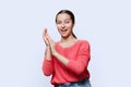 Young teenage girl clapping her hands on white studio background