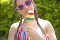 Young teenage girl eating icecream cone wearing pink sunglasses and braids on hot summer Royalty Free Stock Photo