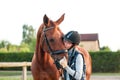 Young teenage girl equestrian kissing her chestnut horse.