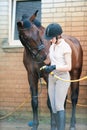 Young teenage girl equestrian preparing to wash her chestnut horse