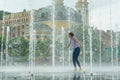 Young teenage girl in fountain. Girl happy, clothes wet, background city architecture.