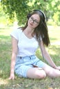 Young teenage girl listening music with headphones and smart phone in the park, summer portrait Royalty Free Stock Photo