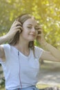 Young teenage girl listening music with headphones and smart phone in the park, summer portrait Royalty Free Stock Photo