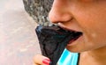 Young teenage girl outdoors eating black ice cream cone on the city Royalty Free Stock Photo