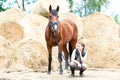 Young teenage girl owner sitting close to her bay horse. Royalty Free Stock Photo