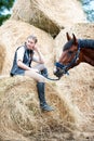 Young teenage girl owner sitting near her red horse