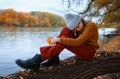 a young teenage girl posing in an autumn forest, she is sad, sitting on a tree by the river bank, beautiful nature and bright Royalty Free Stock Photo