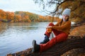 a young teenage girl posing in an autumn forest, sitting on a tree by the river bank, beautiful nature and bright yellow leaves Royalty Free Stock Photo