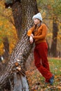 a young teenage girl posing in an autumn forest, she is unhappy and has a sad mood, standing by a tree, beautiful nature and Royalty Free Stock Photo