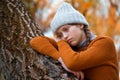 a young teenage girl posing in an autumn forest, she is unhappy and has a sad mood, standing by a tree, beautiful nature and Royalty Free Stock Photo