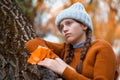 a young teenage girl posing in an autumn forest, she is unhappy and has a sad mood, standing by a tree, beautiful nature and Royalty Free Stock Photo