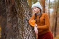 a young teenage girl posing in an autumn forest, she is unhappy and has a sad mood, standing by a tree, beautiful nature and Royalty Free Stock Photo