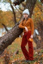 a young teenage girl posing in an autumn forest, she is unhappy and has a sad mood, standing by a tree on the riverbank, beautiful Royalty Free Stock Photo