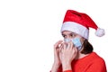 Young teenage girl in red Christmas Santa Claus hat puts on a medical mask, isolated on white background Royalty Free Stock Photo