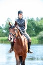 Young teenage girl riding horseback from lake at early morning Royalty Free Stock Photo