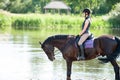 Young teenage girl riding horseback in river at early morning Royalty Free Stock Photo