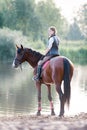 Young teenage girl riding horseback to river at early morning Royalty Free Stock Photo
