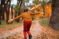 a young teenage girl runs through the autumn forest along a dirt road and enjoys the beautiful nature and bright yellow leaves Royalty Free Stock Photo