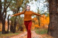 a young teenage girl runs through the autumn forest along a dirt road and enjoys the beautiful nature and bright yellow leaves Royalty Free Stock Photo