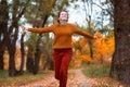 a young teenage girl runs through the autumn forest along a dirt road and enjoys the beautiful nature and bright yellow leaves Royalty Free Stock Photo