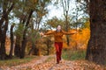 a young teenage girl runs through the autumn forest along a dirt road and enjoys the beautiful nature and bright yellow leaves Royalty Free Stock Photo