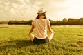 Young teenage girl sits in the park near the river, back view, girl looks at the water, practices yoga, meditates Royalty Free Stock Photo